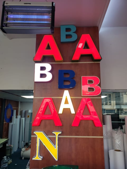 Neon sign with colorful letters spelling ABABABAN, mounted on wooden wall