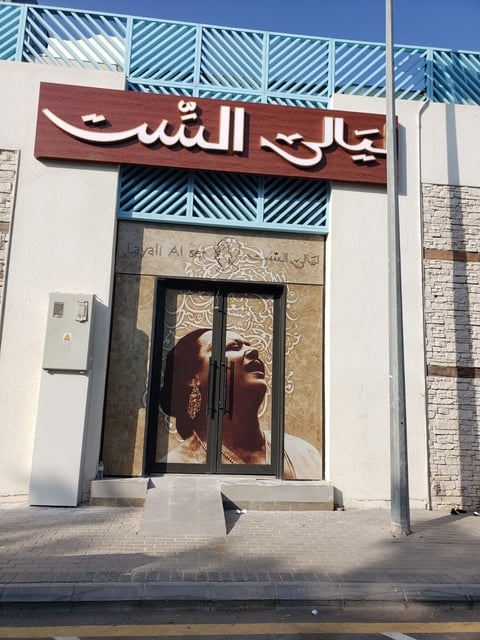 Storefront with red Arabic sign and decorative blue striped awning