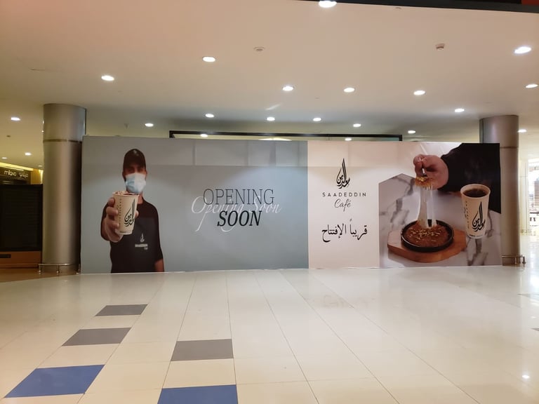 Large opening soon signage in modern mall hallway with coffee shop branding