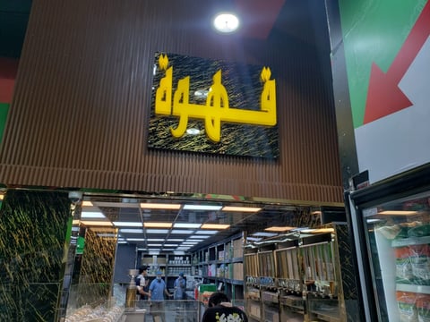 Yellow neon storefront sign with four castle towers above a modern retail shop entrance at night