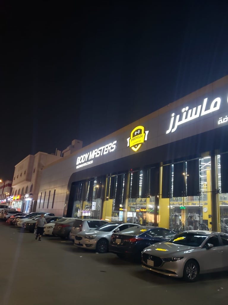 Nighttime exterior view of BodyMasters car showroom with illuminated storefront