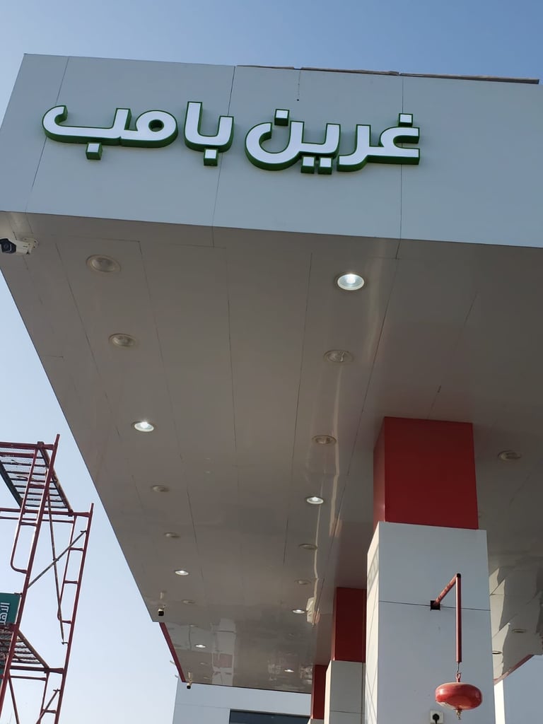 Arabic storefront sign on modern building exterior with white and red architectural elements against blue sky