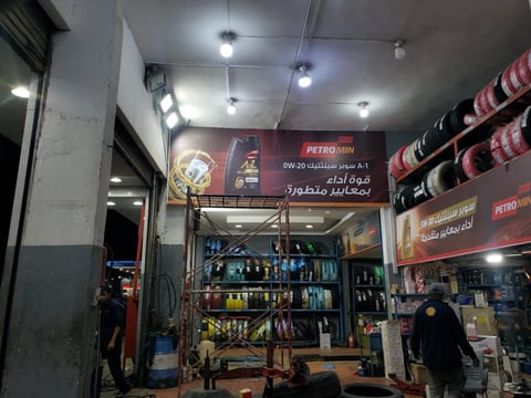 Interior of a Petro Min automotive shop with shelves of products, tools, Arabic signage