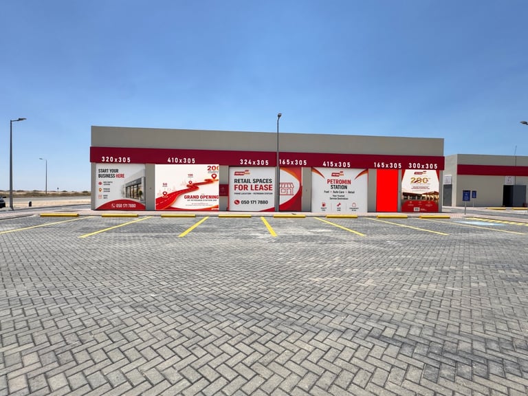 Empty commercial strip mall with red and white storefront signage under clear blue sky