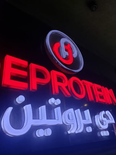 Neon sign displaying red EPROTEIN text with Arabic script and glowing logo