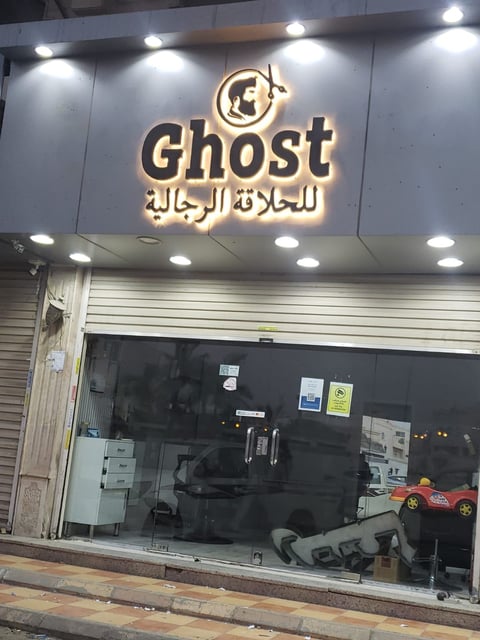 Ghost storefront with illuminated neon sign and Arabic text, displaying toys