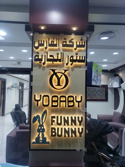 Illuminated storefront sign with Arabic text and YOBABY Funny Bunny branding