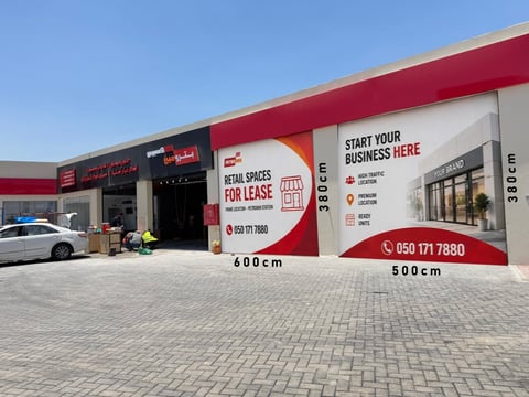 Commercial storefront with red and white branding advertising retail spaces for lease