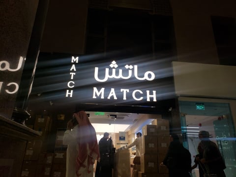 Storefront with illuminated Match signage in Arabic and English