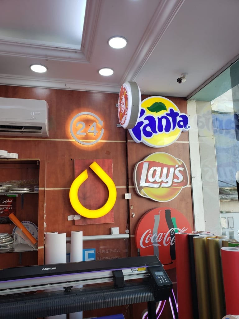 Display window with illuminated neon signs for Fanta, Lays, and Coca-Cola brands against a burgundy wall